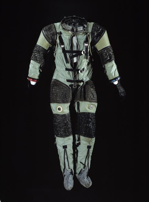 A pale green and black striped suit posed against a black background. 
