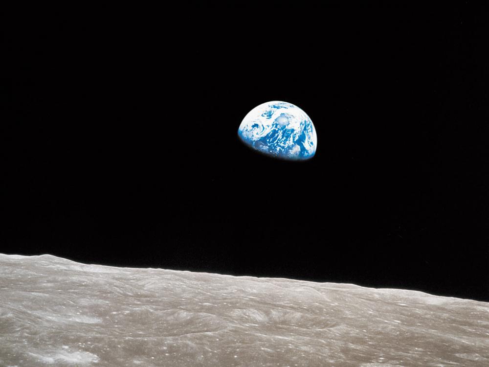 Photo of the Earth rising in the sky with the Moon in the foreground