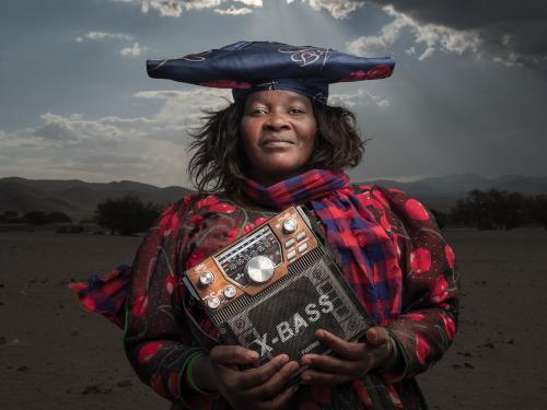 A woman faces the camera holding a large radio.