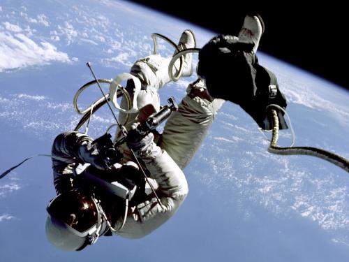 Edward White, a male astronaut, floats in zero gravity with a backdrop of Earth behind him.