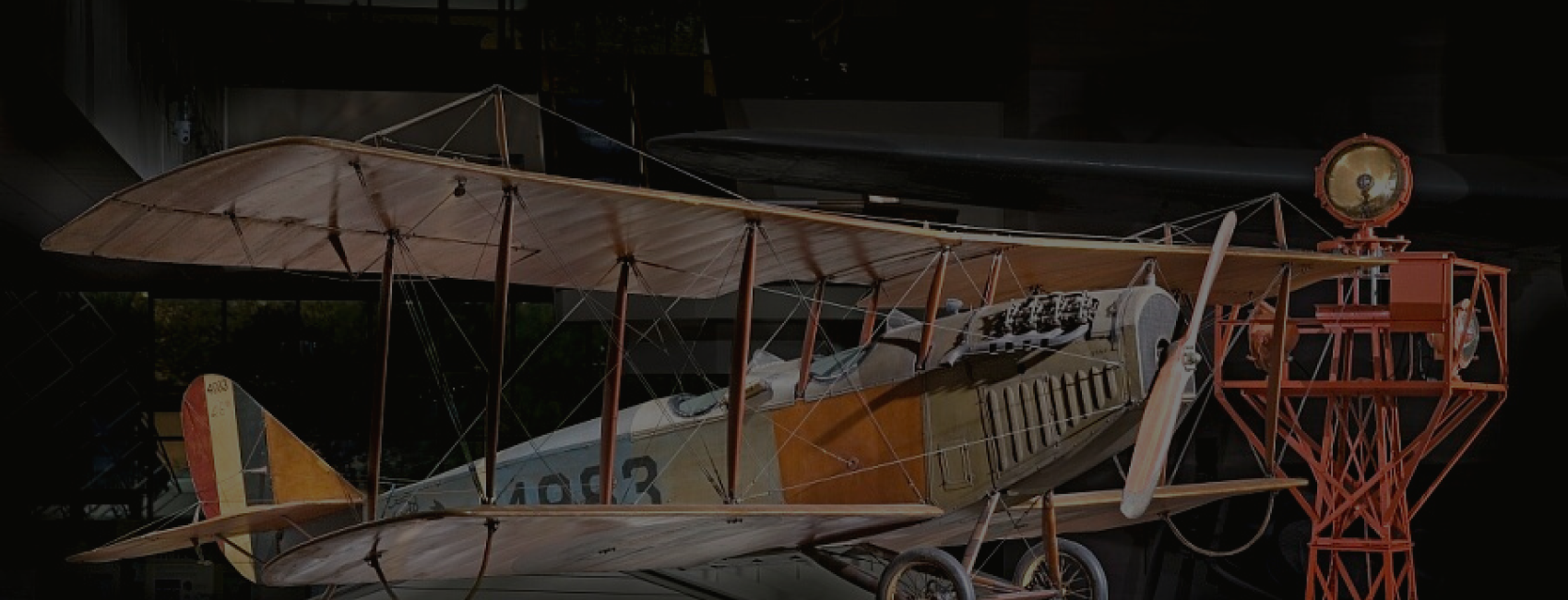 A photo of the Curtiss JN-4D Jenny in a museum gallery. To the left is a signal beacon.