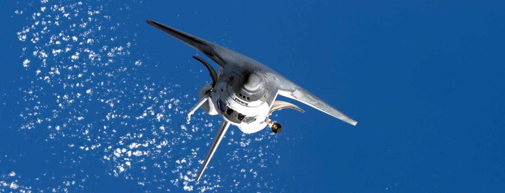 Inverted Space Shuttle Discovery orbits Earth